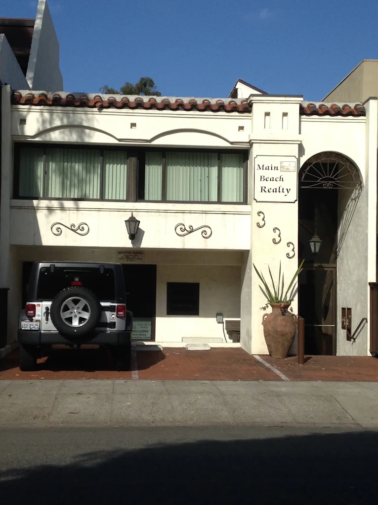 The white Spanish-style building at 333 Third Street, its street number painted beside an arched entrance under a red tile roof, with a Main Beach Realty sign on the front.