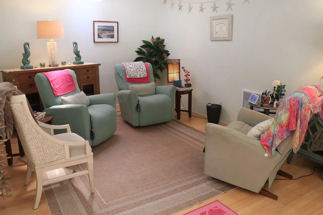 A session room at the practice, two sea-green recliners with throws over them, seahorse lamps on a wooden sideboard and a string of starfish on the wall.